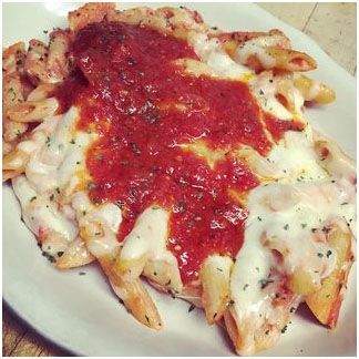 A white plate topped with baked penne pasta dinner