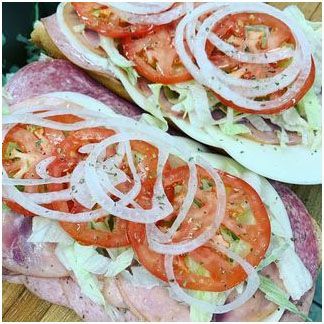 Italian hoagie with tomatoes, onions and lettuce on a wooden table