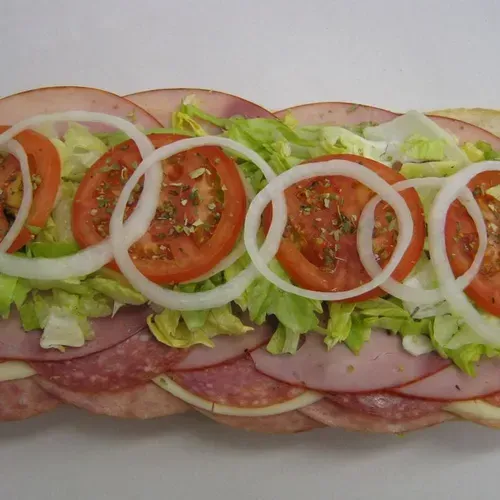 A sub sandwich with ham, lettuce, tomatoes and onions on a white surface