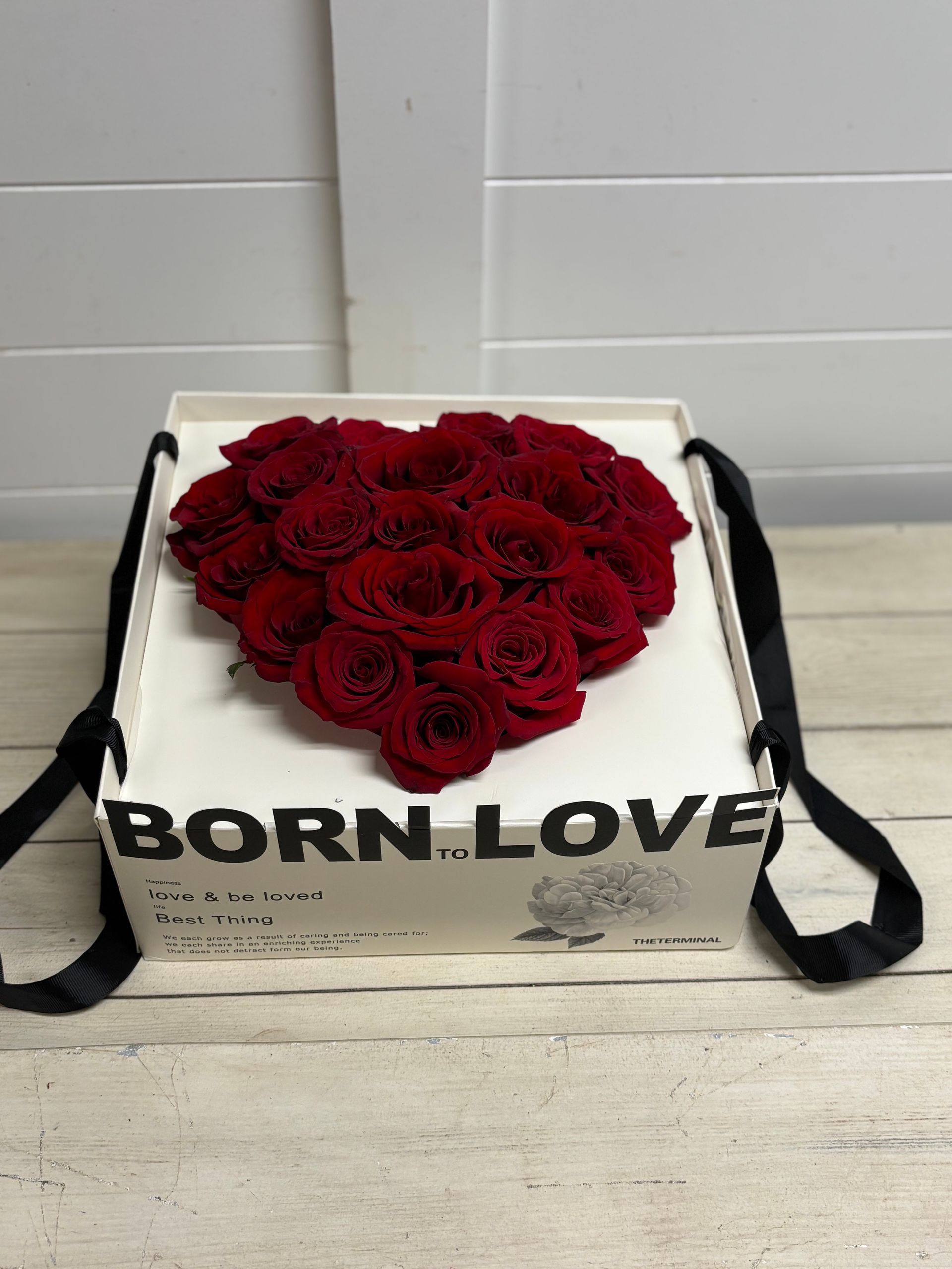 A white gift box with black ribbon handles and the text 