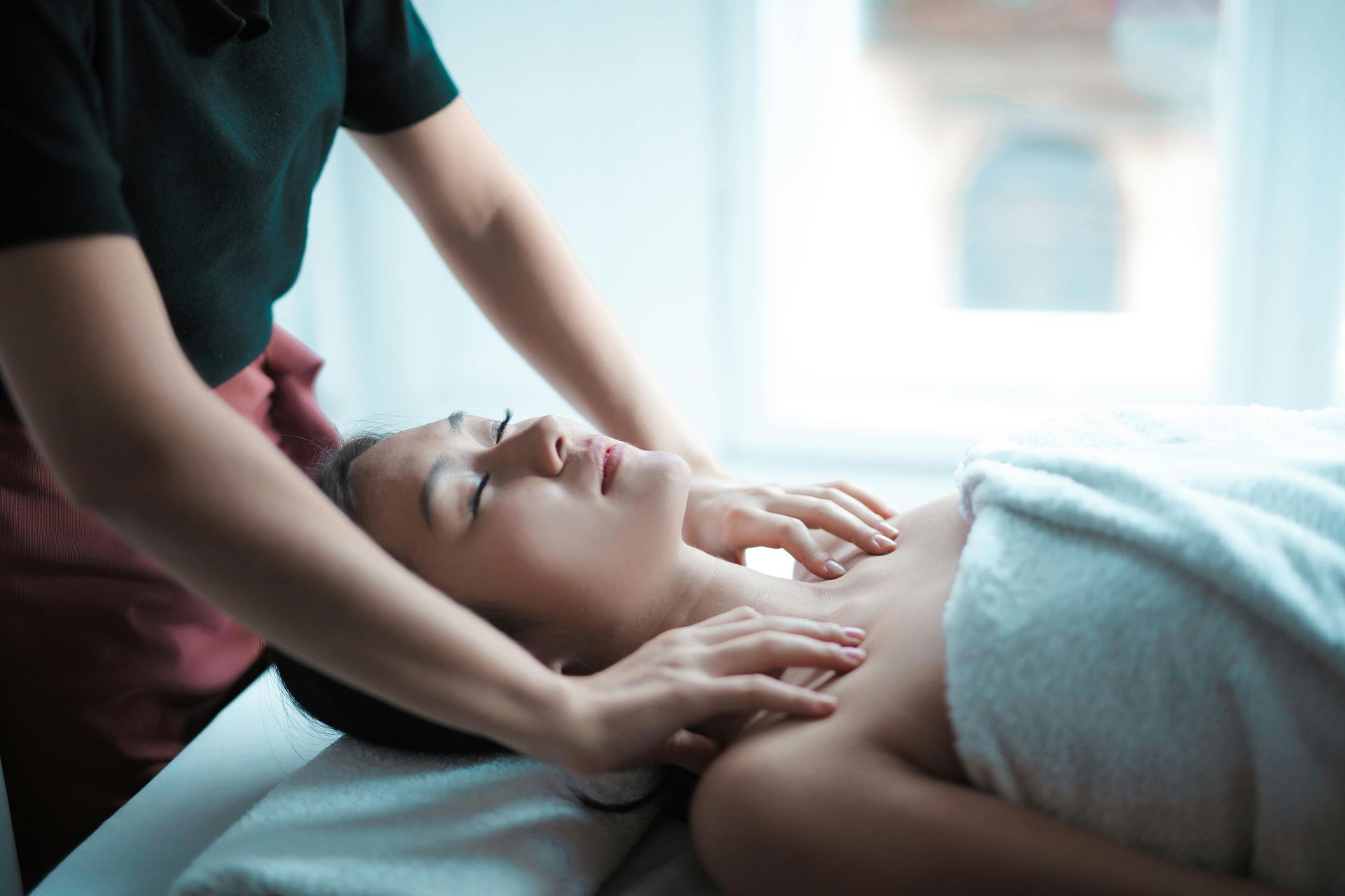 A person receives a relaxing shoulder and neck massage while lying on a spa table.