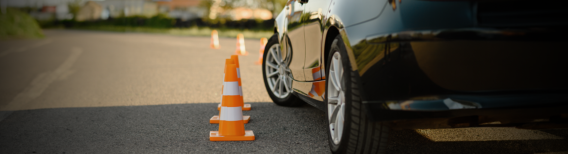 Um carro está estacionado próximo a um cone de trânsito na beira da estrada.