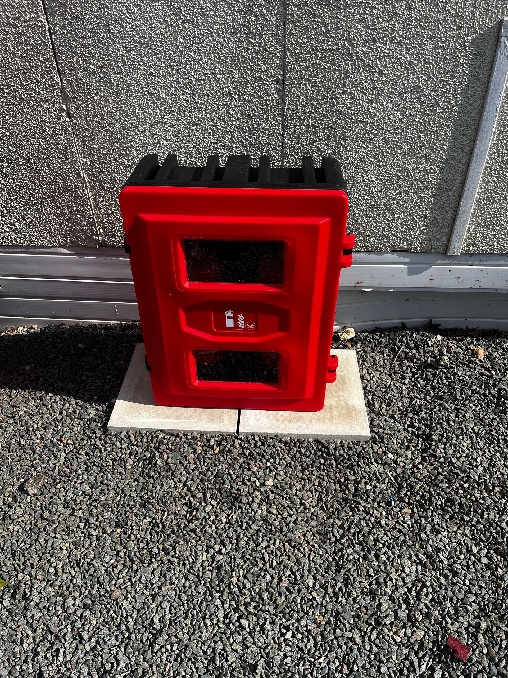 A red box is sitting on top of a pile of gravel.