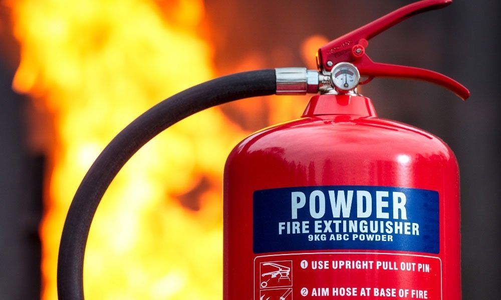 A red powder fire extinguisher in front of a fire