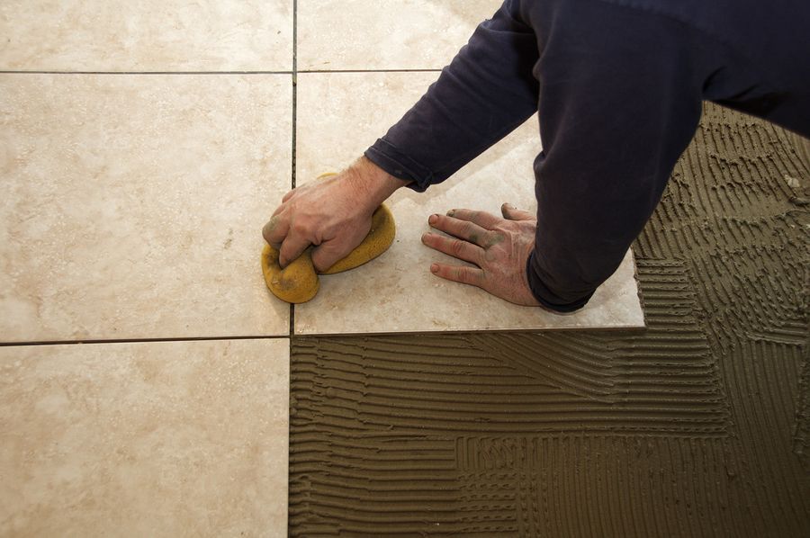 A man is cleaning a tile floor with a sponge