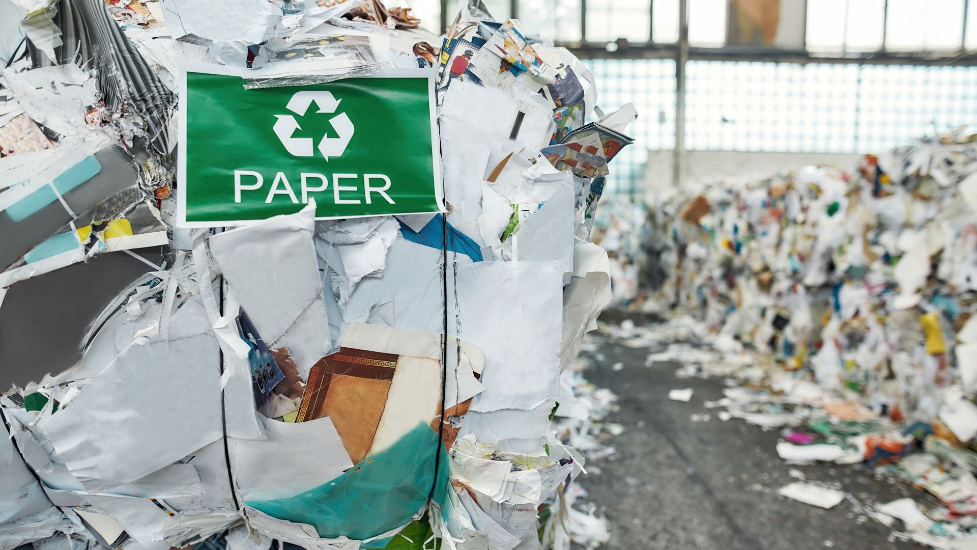 A pile of shredded paper is sitting next to a recycling sign.