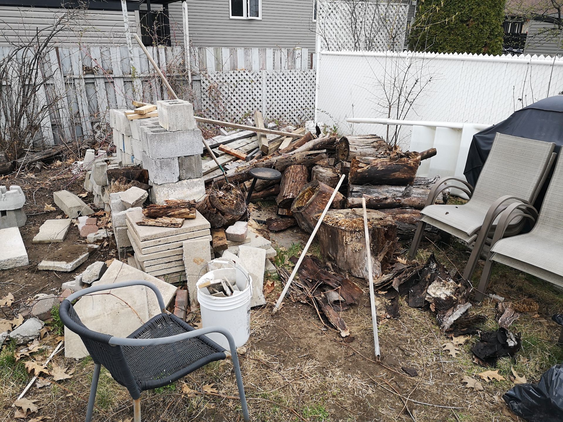 A pile of wood is sitting on the ground in a backyard.