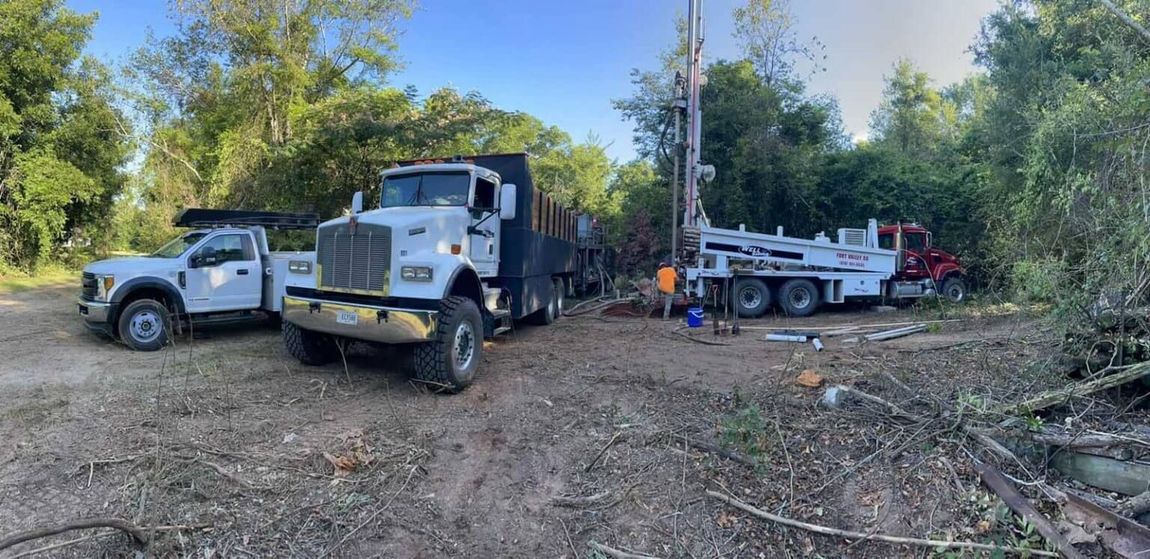 Two trucks are parked next to each other in a dirt field.