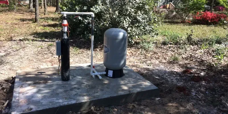 A water pump is sitting on top of a concrete platform in a yard.