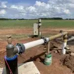 A water pump is sitting in the middle of a field.