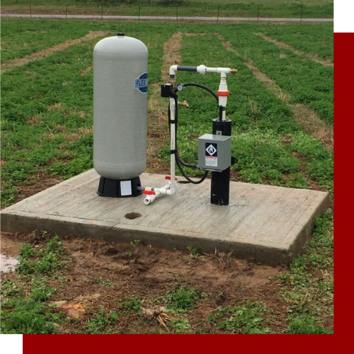 A water pump is sitting on top of a concrete platform in a field.