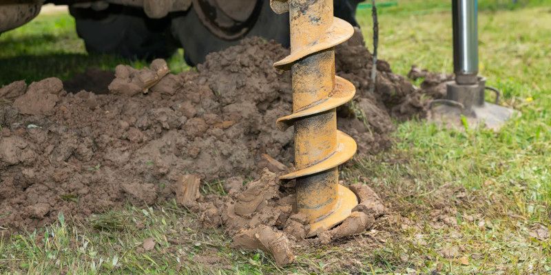 A person is using a drill to dig a hole in the ground.