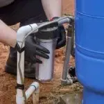 A person is installing a water filter into a water tank.