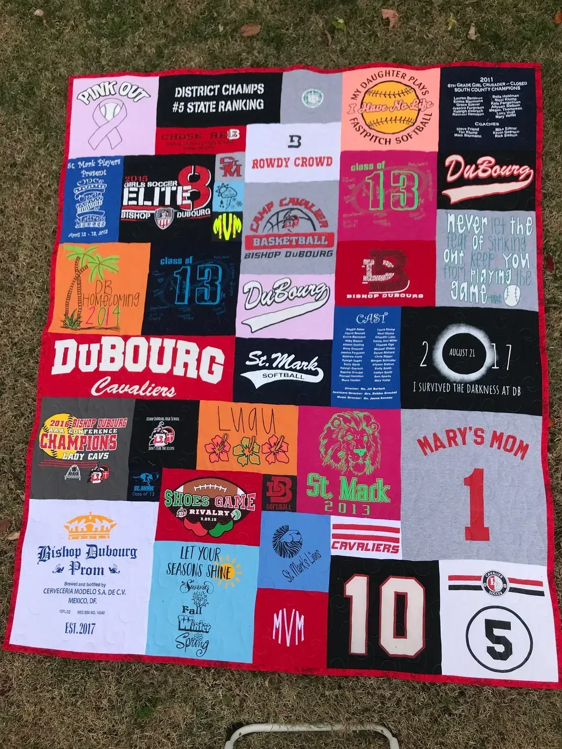A colorful quilt made from various square fabric patches featuring sports team names, numbers, and graphic designs.