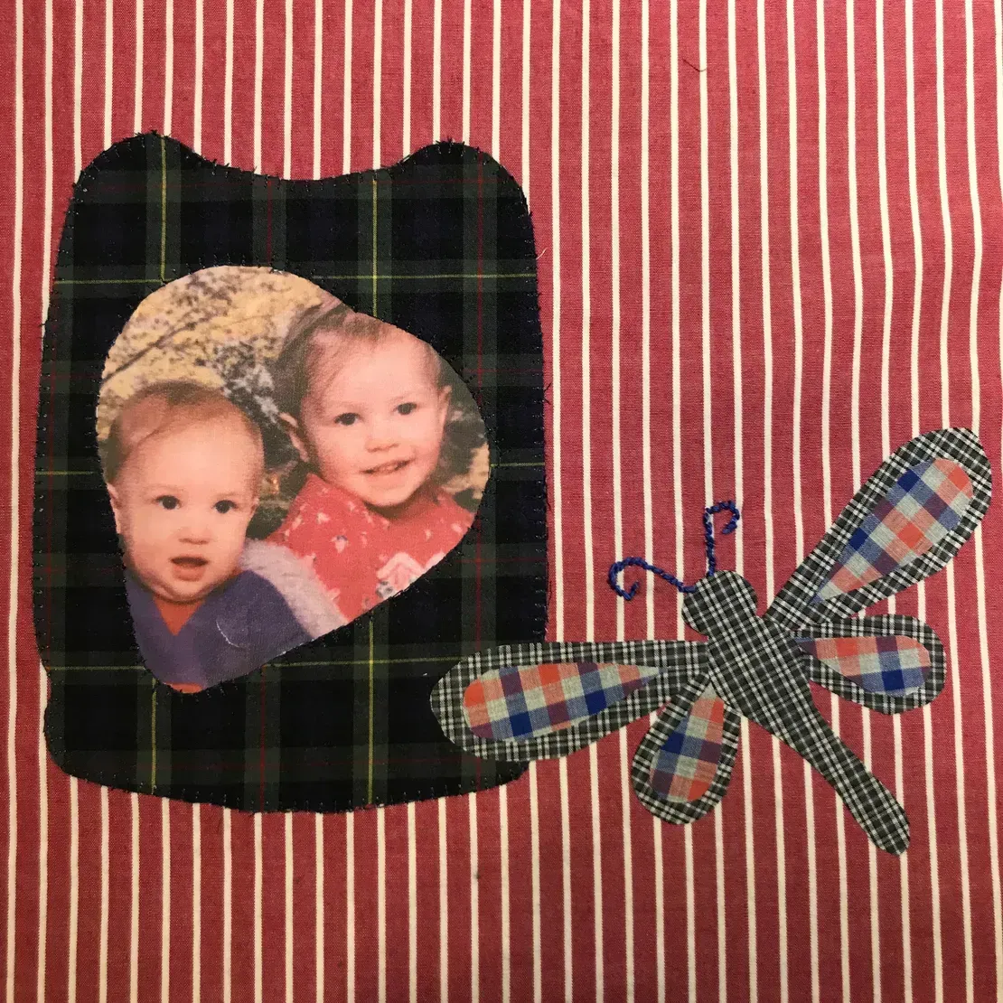 A fabric wall hanging featuring a photo of two children inside a plaid frame next to a plaid dragonfly