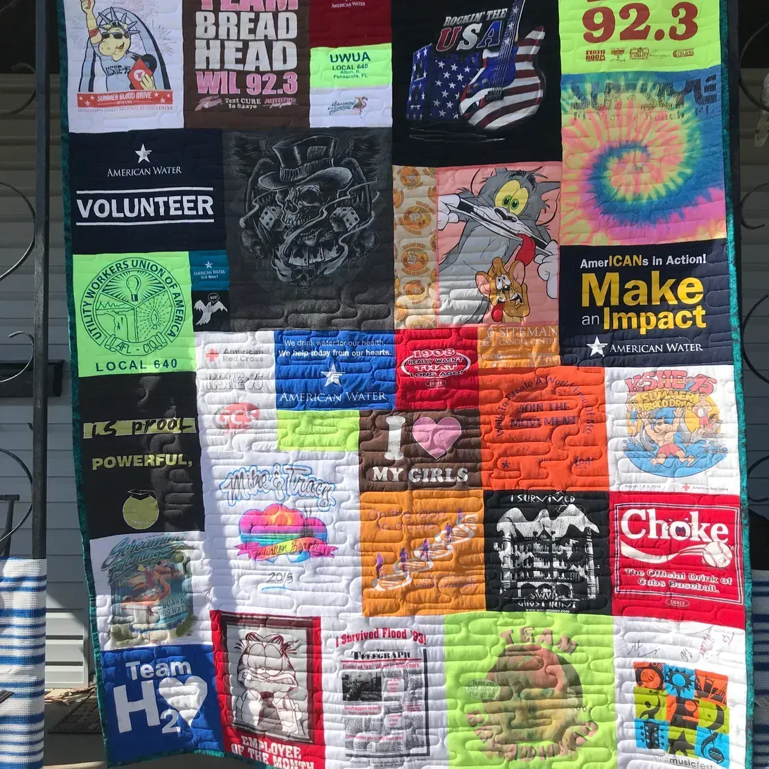 A patchwork quilt made of various colorful graphic t-shirts featuring logos, slogans, and cartoon characters.