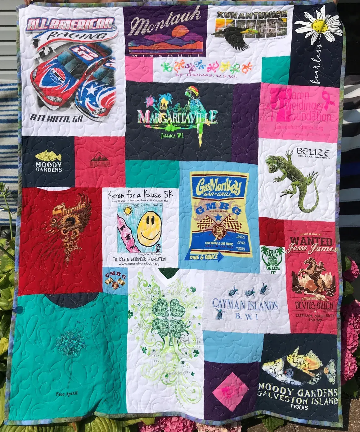 A colorful quilt made from various souvenir t-shirts featuring graphics of animals, beaches, and travel destinations.