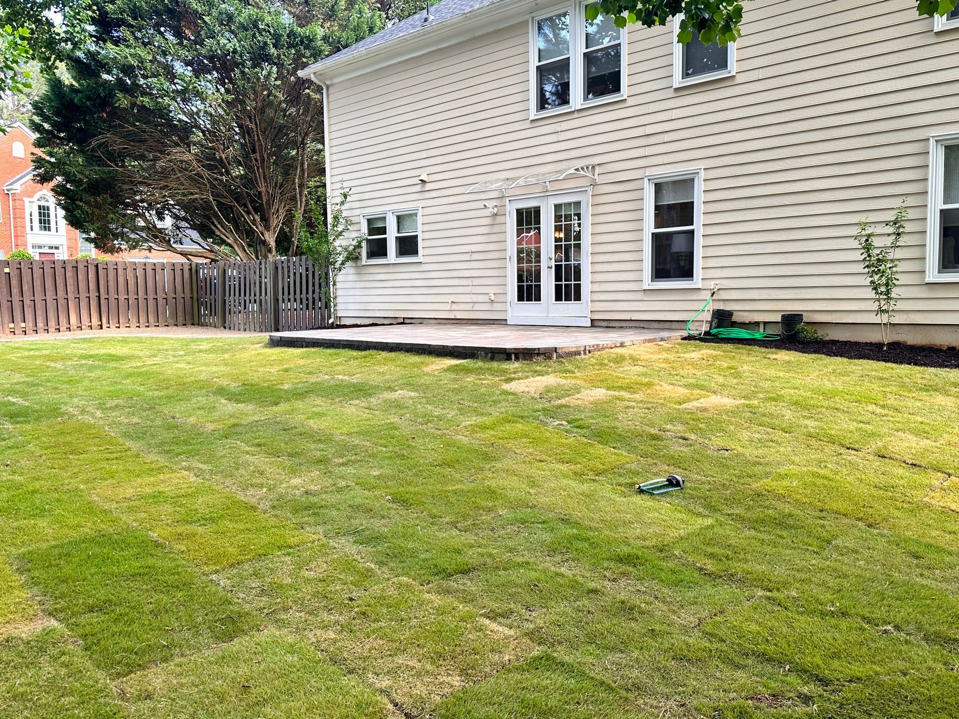 The backyard of a house with a lush green lawn and a deck.