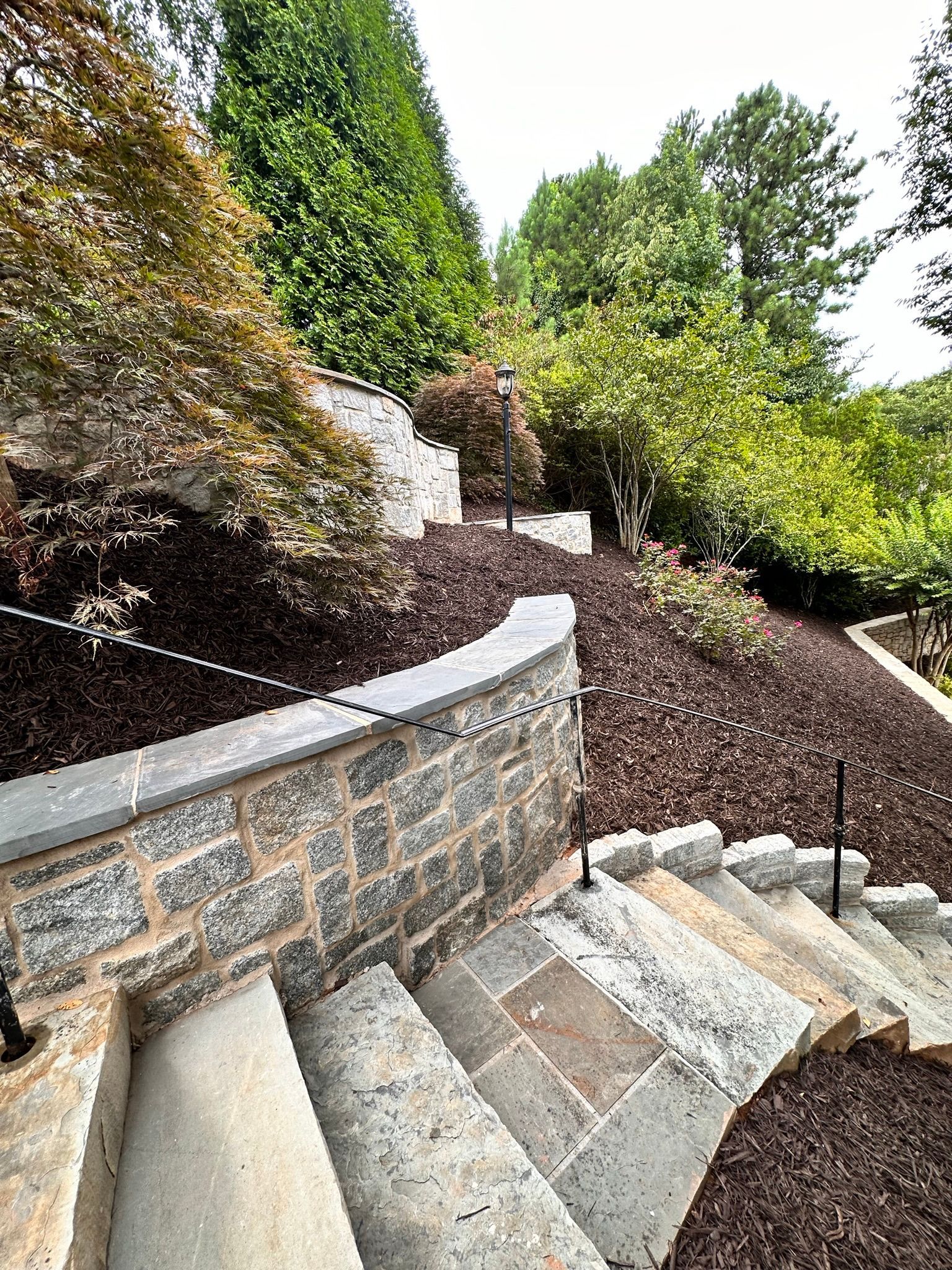 A set of stairs leading up to a stone wall in a garden.