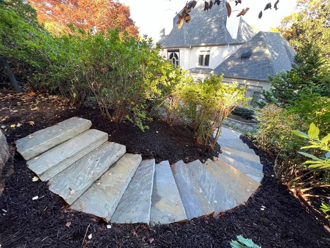 A circular stone walkway in a garden with a house in the background.