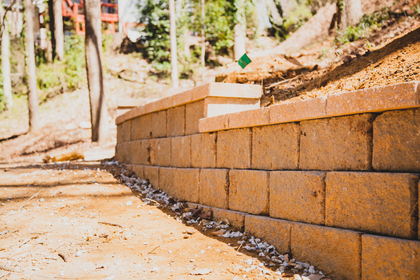 A brick wall is sitting on top of a dirt hill.