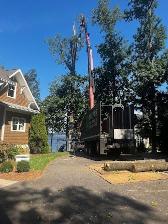 A truck is cutting down a tree in front of a house.