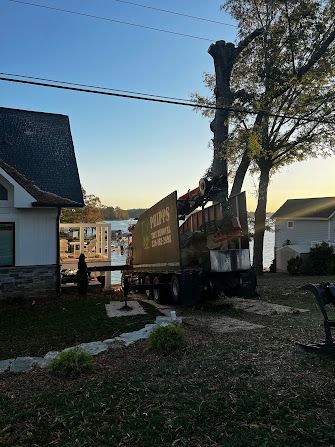 A truck is cutting down a tree in front of a house.