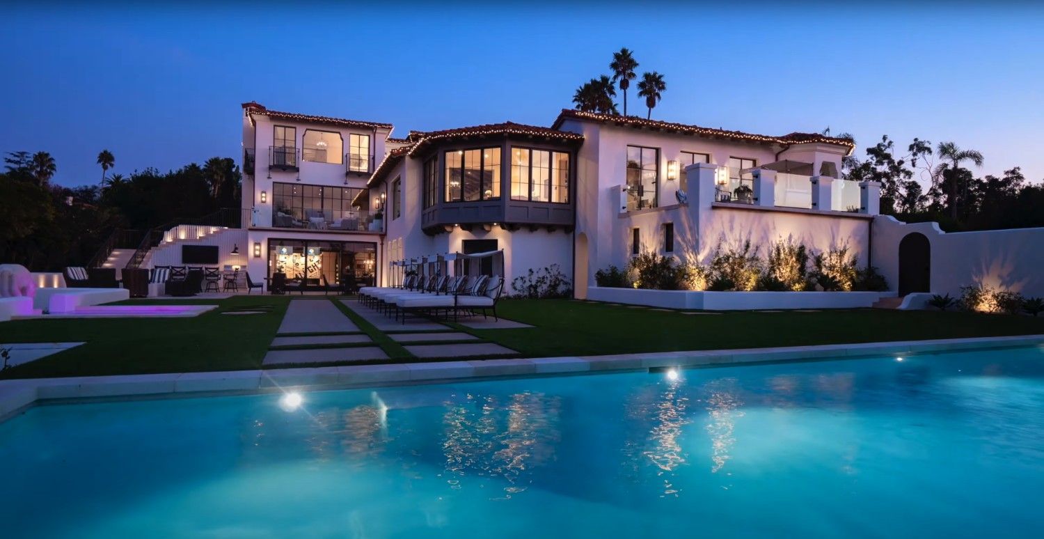 A large house with a swimming pool in front of it at night.