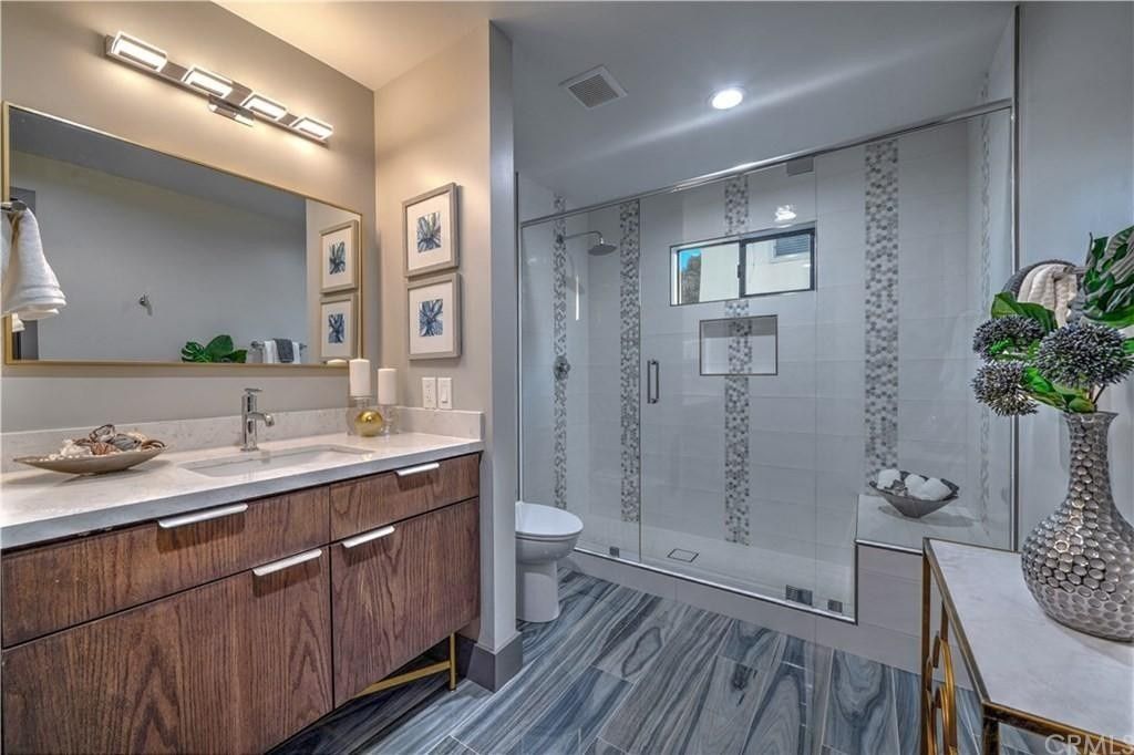 A bathroom with a sink , toilet , shower and mirror.