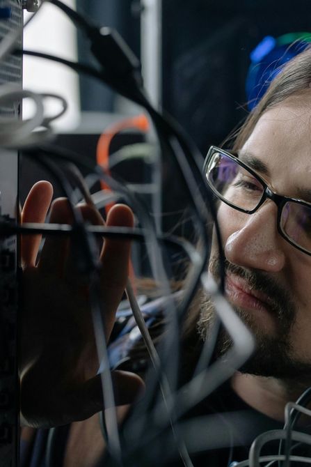 A man wearing glasses is looking at a bunch of wires