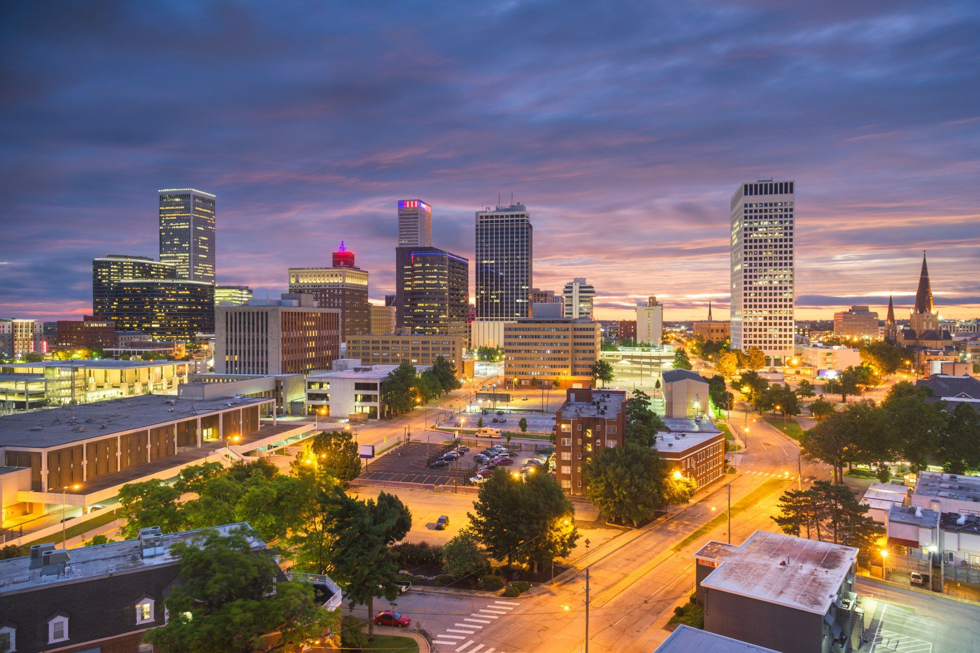 An aerial view of Tulsa Oklahoma at night with a lot of buildings and trees.
