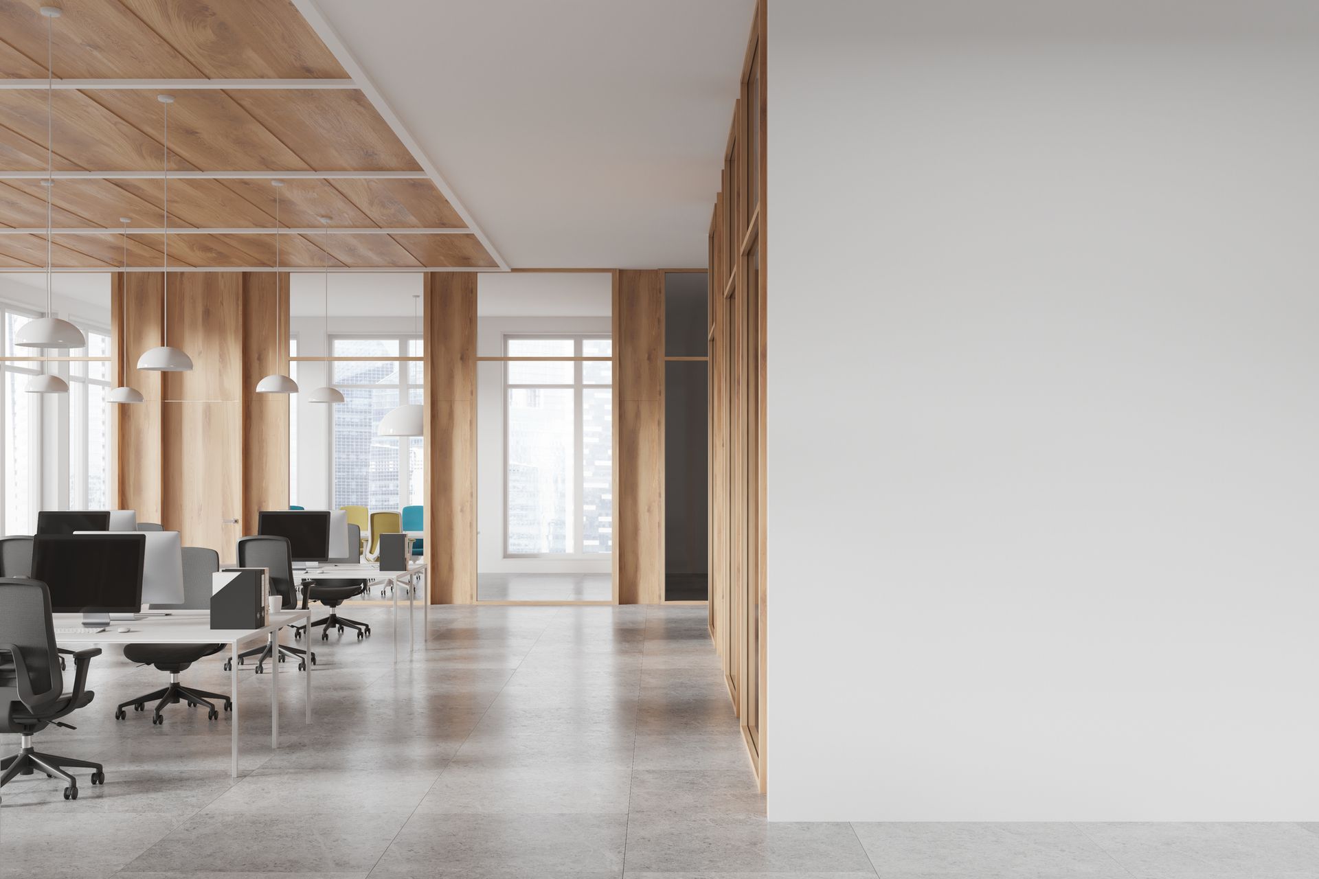 Modern office space with a gray tiled floor, wooden accents, and rows of desks and chairs. Bright windows offer an outdoor view.