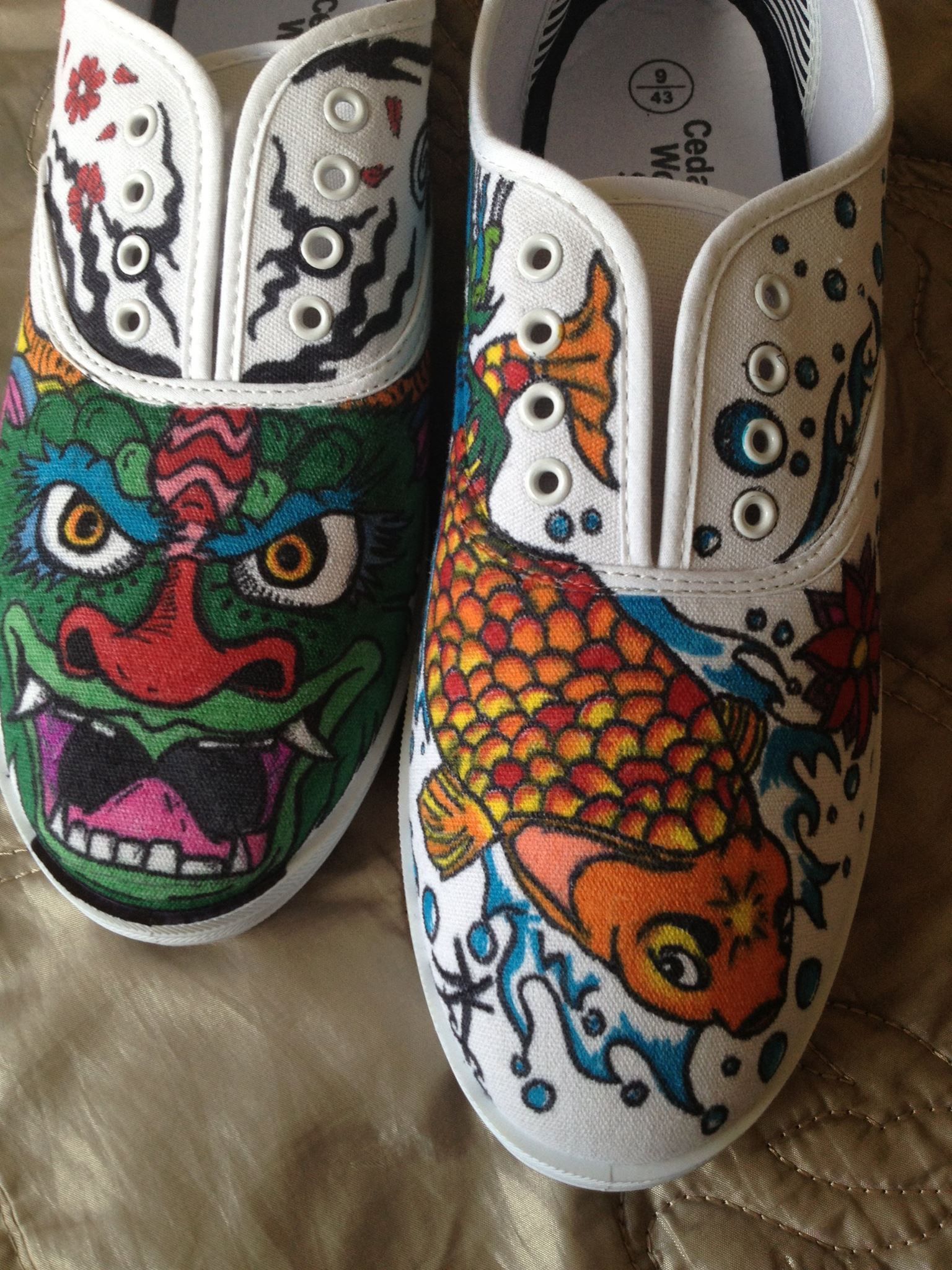 A pair of shoes with a dragon and a fish drawn on them in sharpie pens