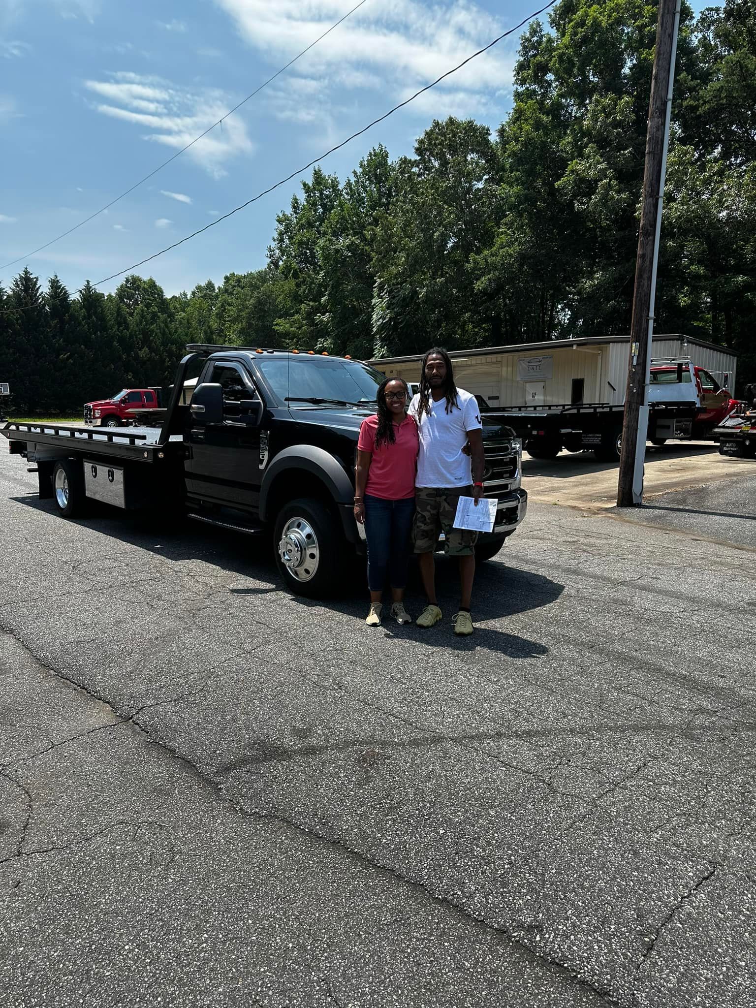 A man and woman are standing in front of a tow truck.