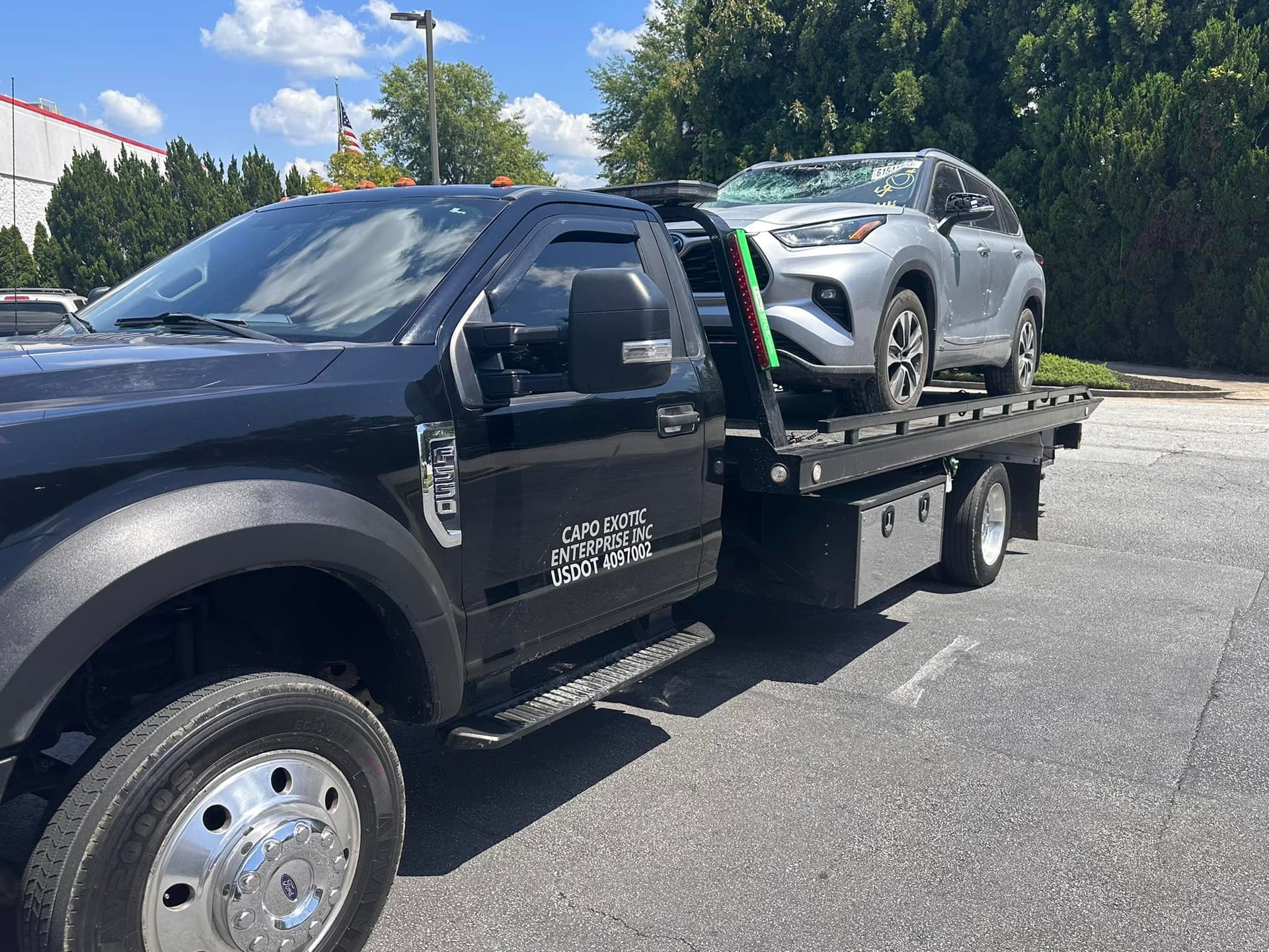 A tow truck is towing a car in a driveway.