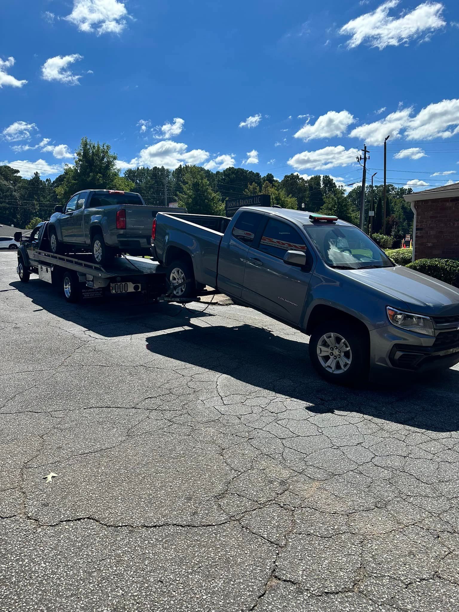 A tow truck is towing a car in a driveway.