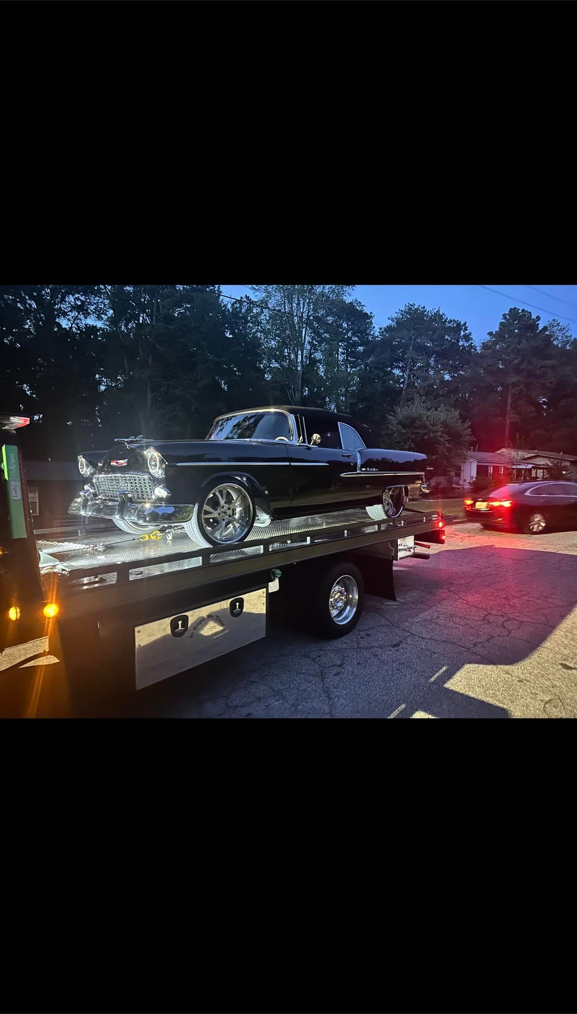 A tow truck is towing a car in a driveway.
