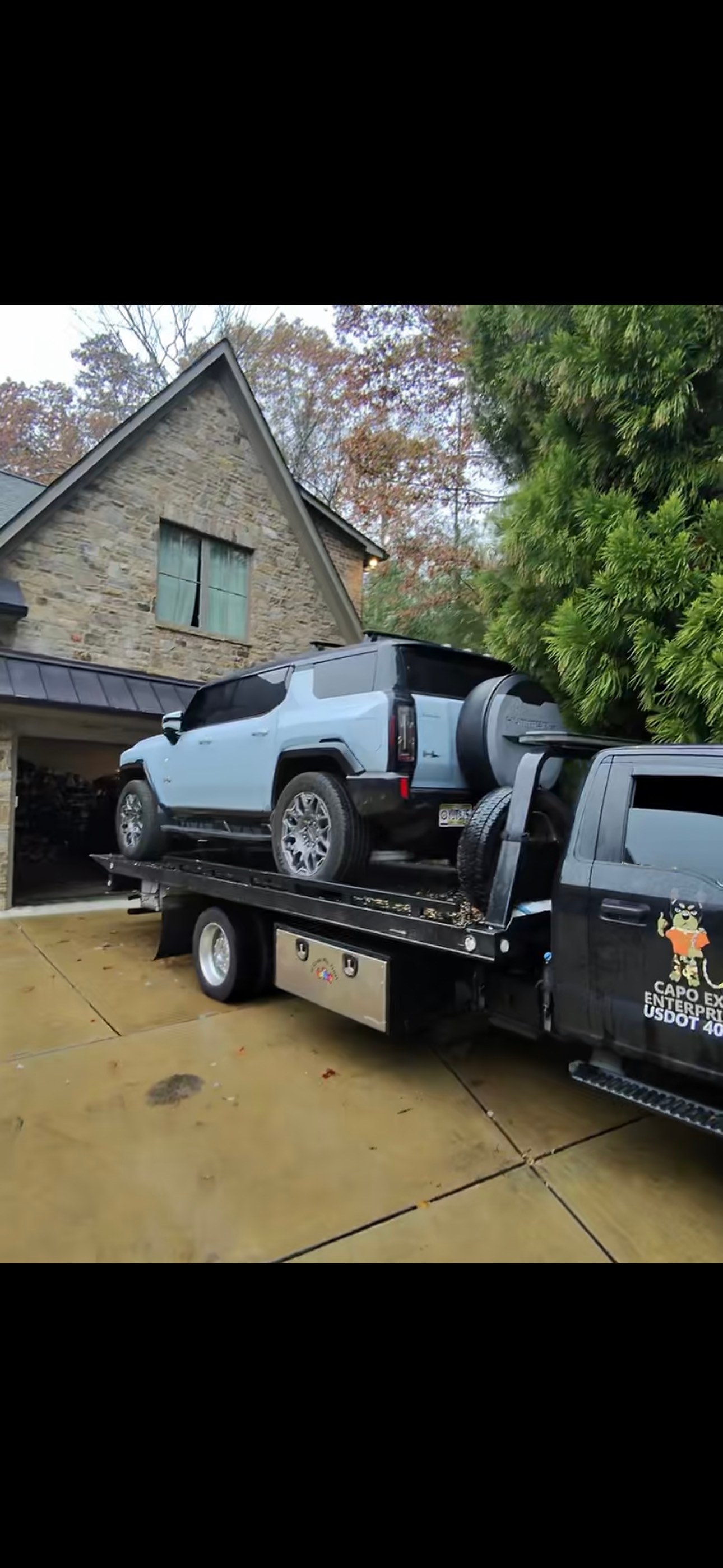 A tow truck is towing a car in a driveway.