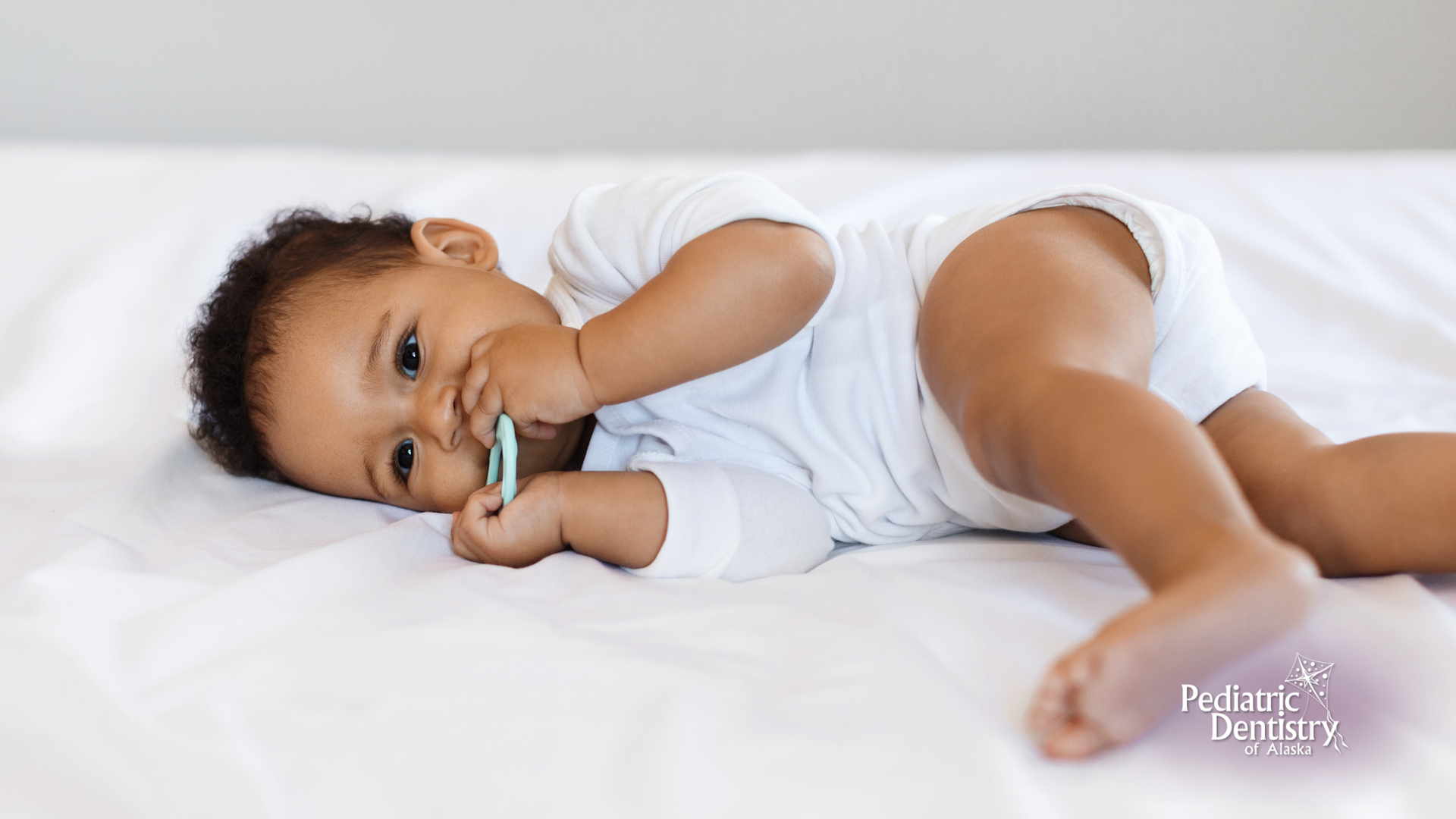 A baby is laying on a bed with a pacifier in his mouth.