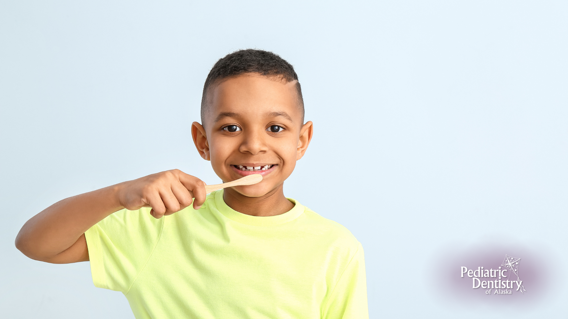 A young boy is brushing his teeth with a wooden toothbrush.