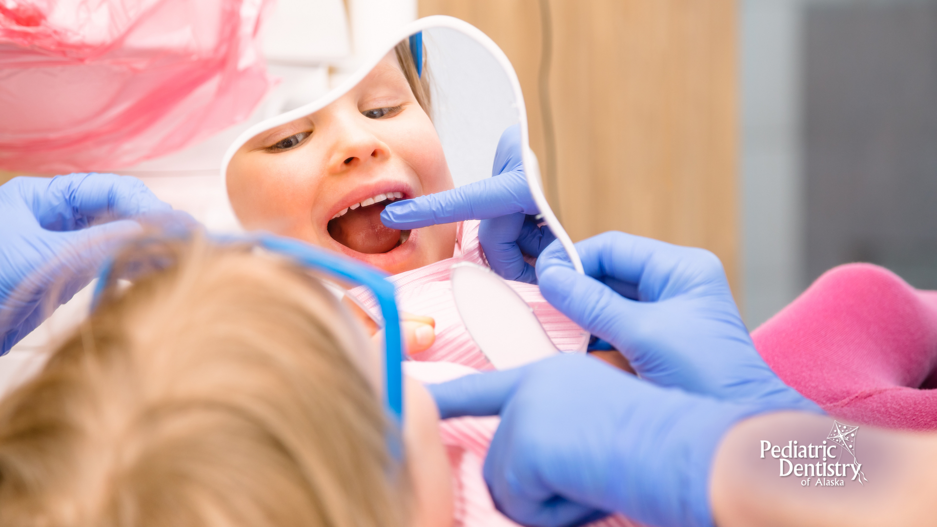 A little girl is getting her teeth examined by a dentist.