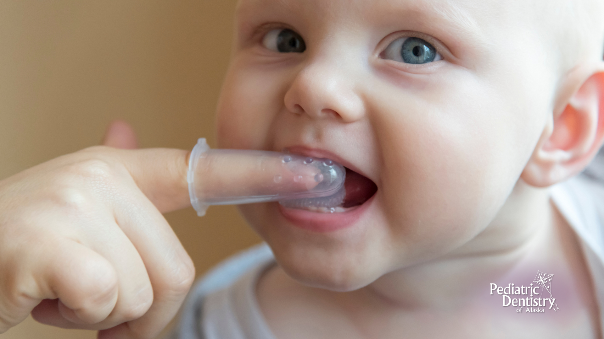 A baby is brushing his teeth with a finger brush.