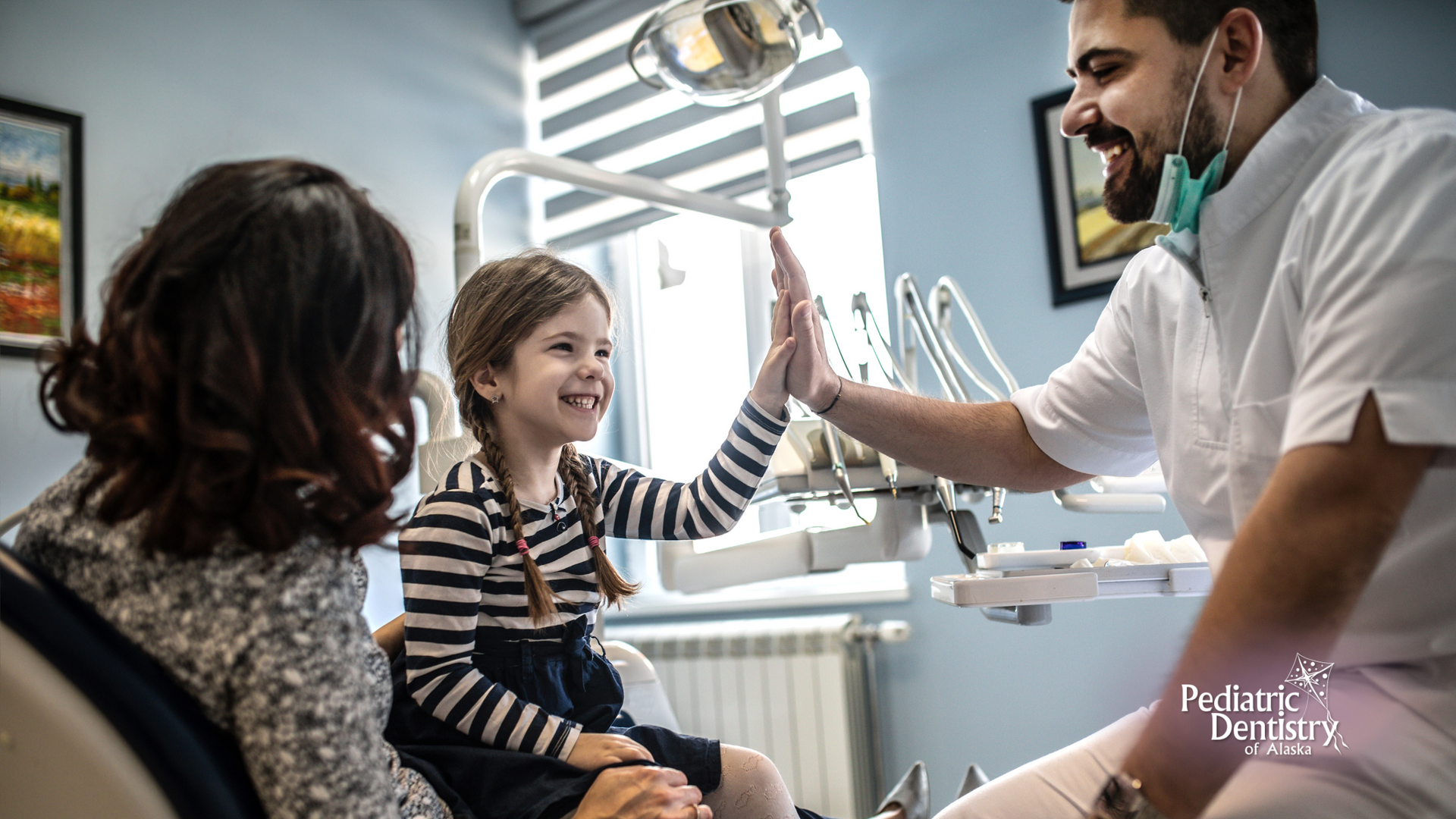 A little girl is giving a high five to a dentist in a dental office.