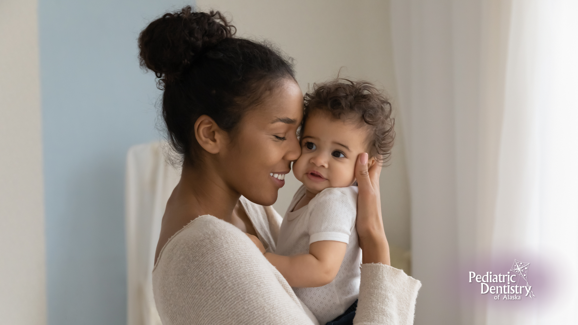 A woman is holding a baby in her arms and kissing it on the cheek.