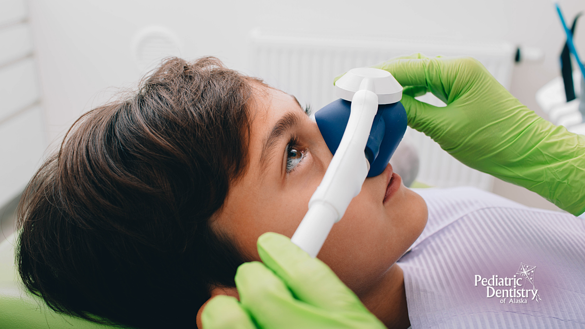 A young boy is laying in a dental chair with an oxygen mask on his nose.