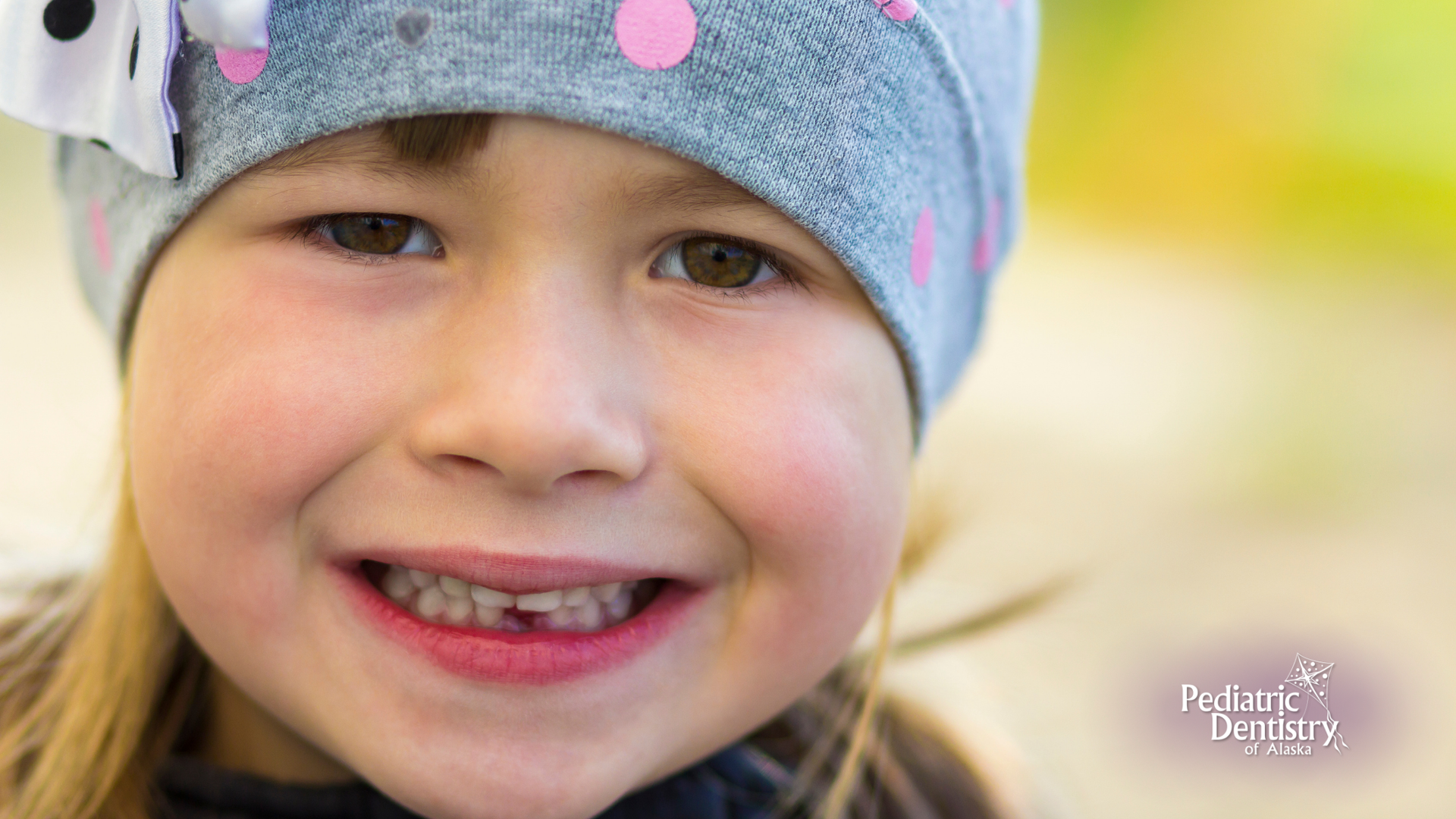 A close up of a little girl wearing a hat and smiling.