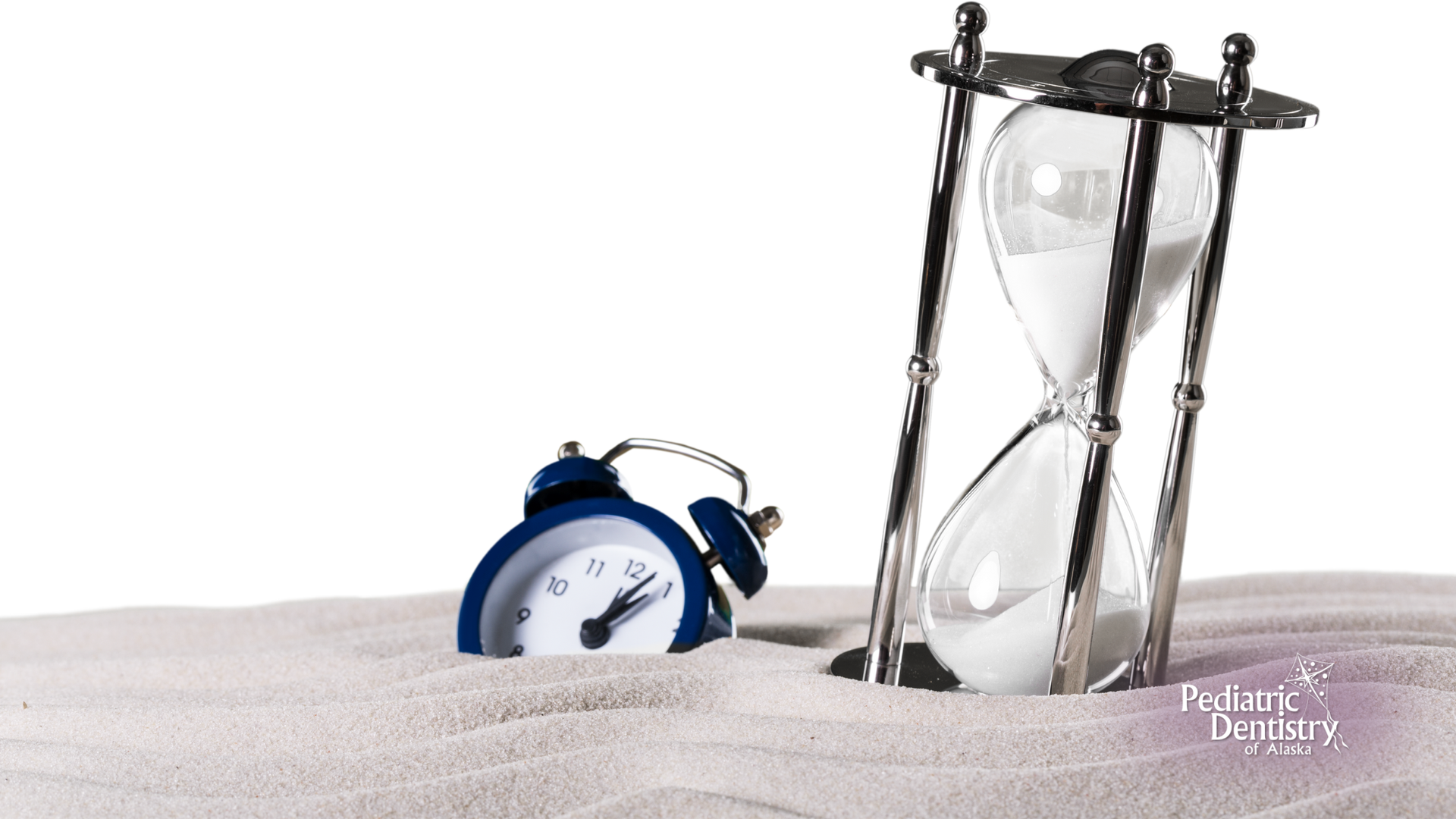 An alarm clock buried in sand next to a silver hourglass, on a white background.