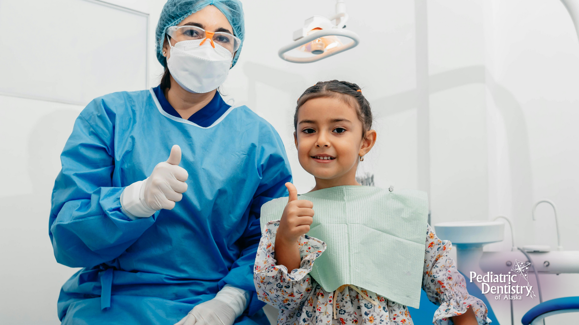 A dentist and a little girl are giving a thumbs up in a dental office.