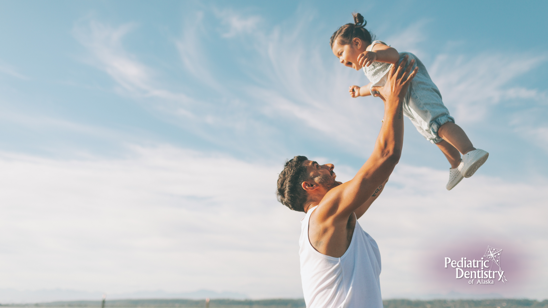 A man is holding a little girl in the air.