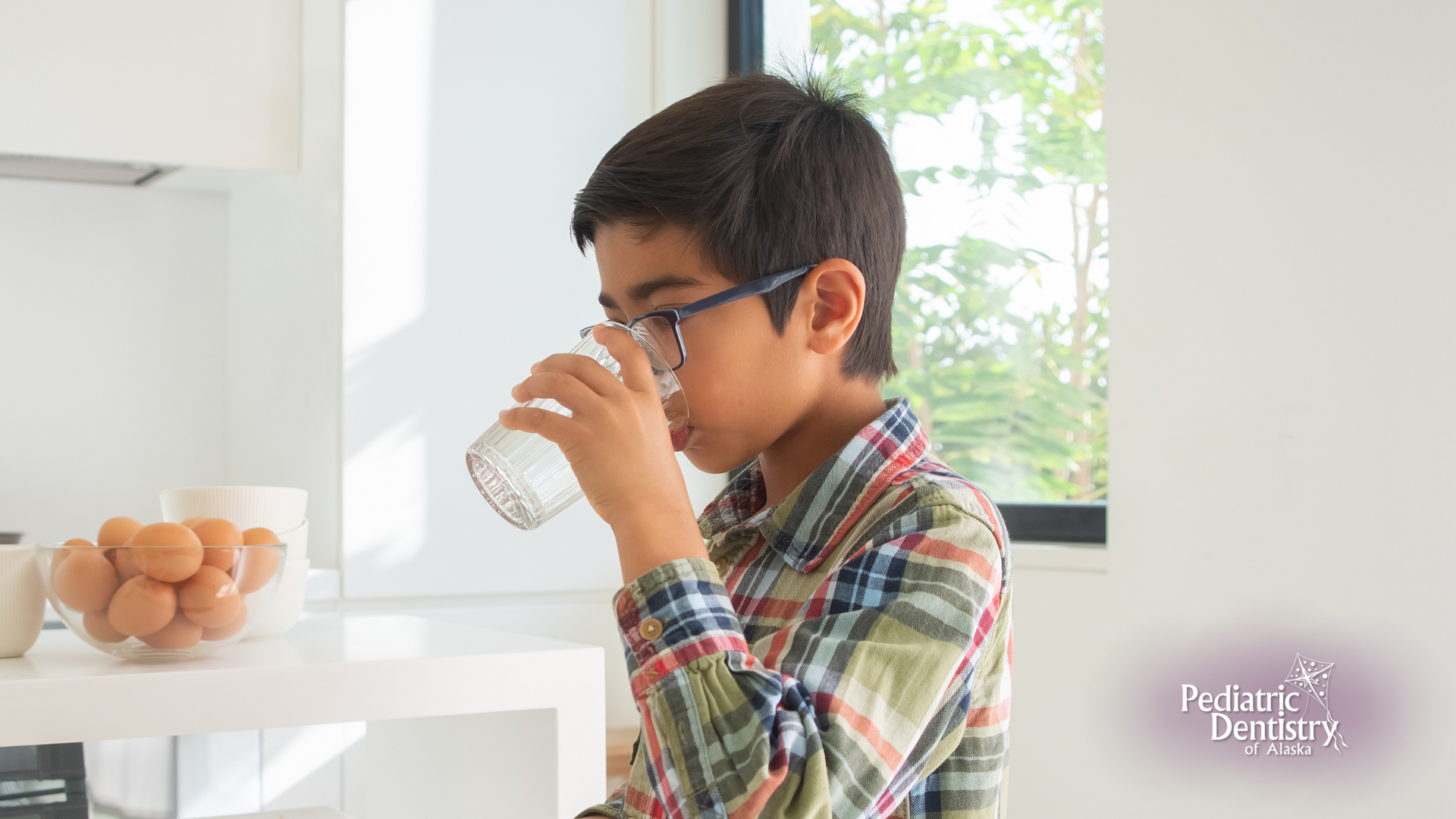 A young boy is drinking milk from a glass in a kitchen.